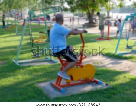 Blurred picture : Old man exercising on fitness bikes at park.