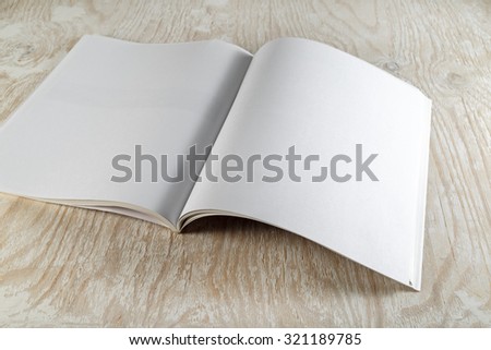 Photo. Open brochure magazine with soft shadows on wooden background . Vintage style photo. Mock-up for graphic designers portfolios.