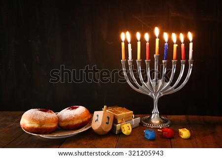 image of jewish holiday Hanukkah with menorah (traditional Candelabra), donuts and wooden dreidels (spinning top). retro filtered image 