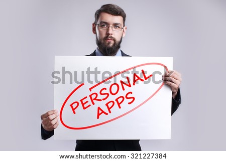 Businessman holding in the hands white poster with handwriting red text "Personal apps". Business, internet, technology concept.