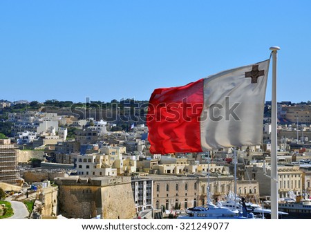 The majestic Maltese flag proudly waving in the gentle Mediterranean breeze, set against the enchanting backdrop of the historic Sliema old town Royalty-Free Stock Photo #321249077