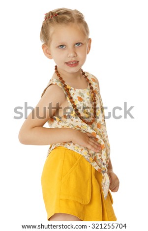 Fashionable little blonde girl in the yellow shorts and the pink blouse. On the neck the girl has a beautiful amber necklace. The plan-Isolated on white background