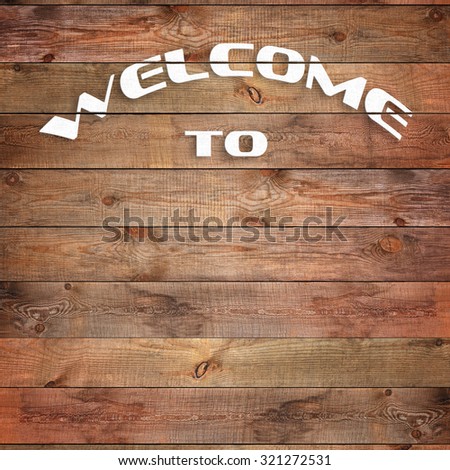 Vintage WELCOME TO sign on natural wooden surface. Closeup.