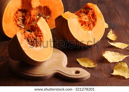 pumpkin cut with leaves on chalkboard on wooden background