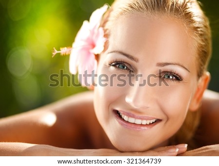 Young beautiful girl lying on massage table in a tropical surroundings - close up.