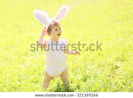 Happy baby with rabbit ears in sunny summer day