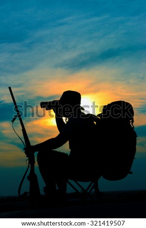 Silhouette of hunter in beautiful sunset on desert with trigger