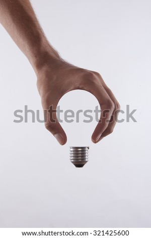 abstract conceptual image of a male's hand holding a light bulb shape