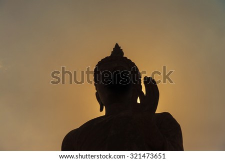 Buddha statue with dark silhouette with golden sunlight in evening