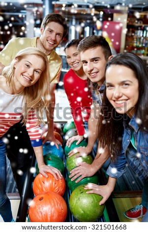 people, leisure, sport, friendship and entertainment concept - happy friends in bowling club at winter season