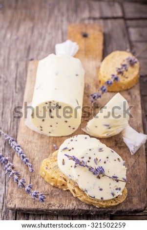 Fresh homemade butter with lavender flowers in a rolled parchment on a wooden cutting board with lavender flowers. The concept of natural organic food home. selective Focus
