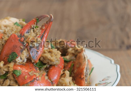 Thai food; Fried crabs with eggs and curry on dish by cropped picture with empty space on right hand side.