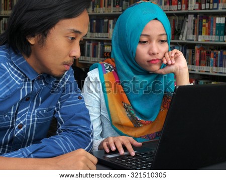 Two students studying together in a library.
