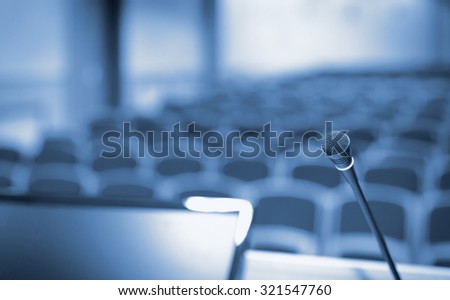 Rostrum with microphone and computer in conference hall Royalty-Free Stock Photo #321547760