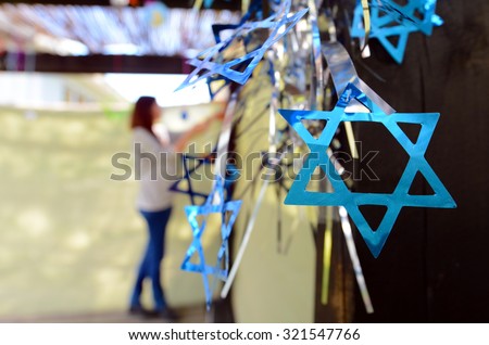 Jewish woman decorating here family Sukkah for the Jewish festival of Sukkot. A Sukkah is a temporary structure where meals are taken for the week. Royalty-Free Stock Photo #321547766
