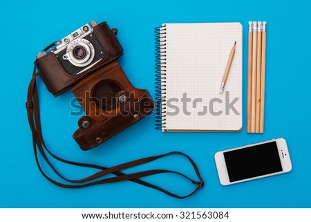 Retro camera and notepad on blue background