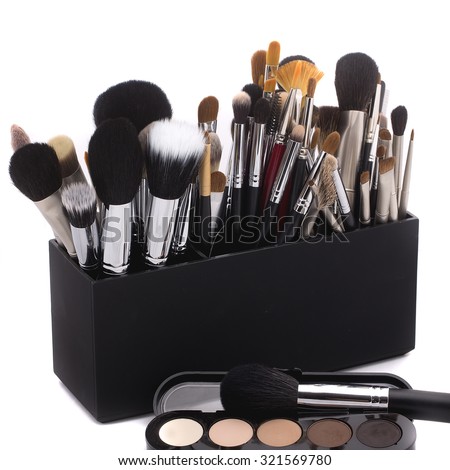 Set of professional soft make-up brushes for eyeshadow powder and facial foundation for visagistes black and brown colors in plastic box with eyeshadow palette on white background, square picture