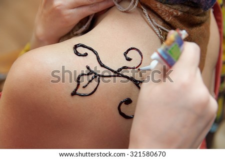  process of applying Mehndi on a woman's shoulder close