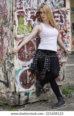 Young woman dancer on graffiti background. Dancing and urban culture concept. Film grain effect

