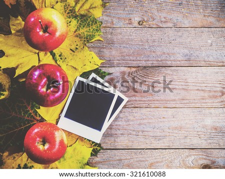 Autumn background with colorful leaves and apples on rustic wooden board. Creating fall season memories with retro photo cards of photo frames. Thanksgiving and Halloween holidays concept. Copyspace