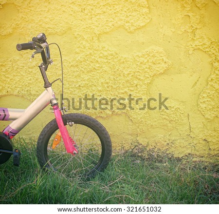 kid bicycle next to yellow textured wall