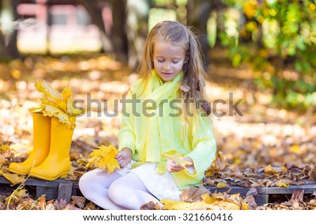 Adorable little girl with a pumpkin for Halloween outdoors at beautiful autumn day