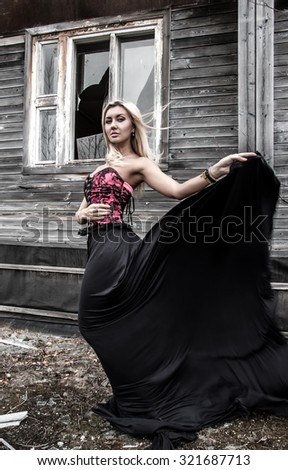 Gorgeous woman at the background of the abandoned wooden house