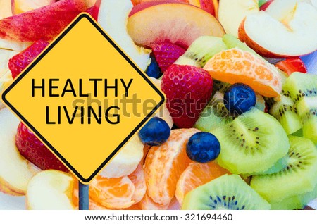 Yellow roadsign with message HEALTHY LIVING over background of healthy fresh fruits