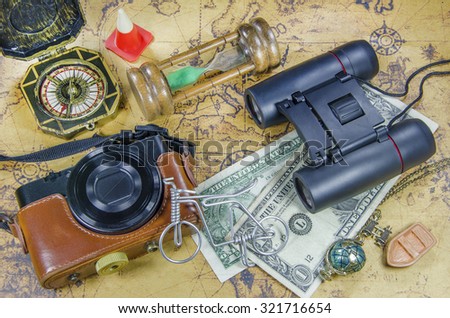 travel picture set with pocket camera binocular compass hourglass money on old world map
