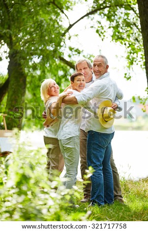 Happy family with senior people embracing in a garden in summer