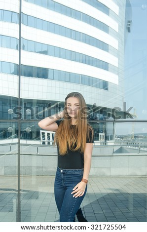 Beautiful young stylish girl with piercings and long hair standing on the building background