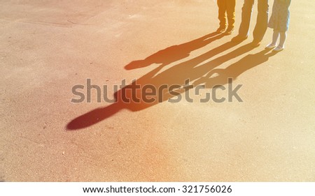 Shadows of mother with son and daughter holding hands on the road