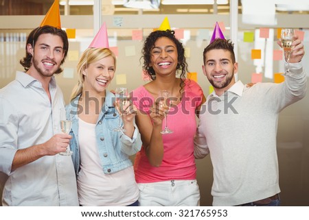 Portrait of happy colleagues holding champagne flute in birthday party at creative office
