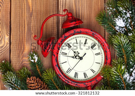 Christmas clock and snow fir tree over wooden background