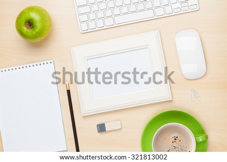Photo frame on office table with notepad, computer and coffee cup. View from above