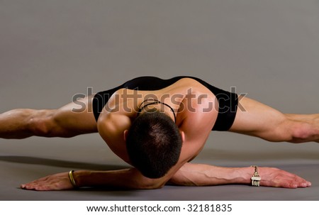 Young muscular dancer posing over gray background
