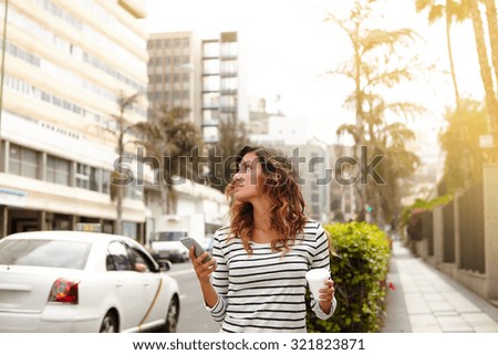 Young lady with brown hair walking on city street and looking away - focus on foreground