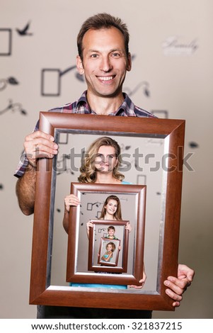 Happy father holding portrait with his family each is located inside their own frame 
