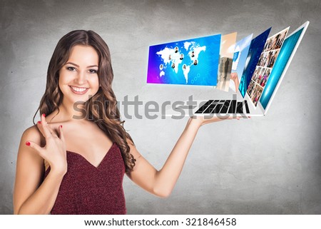 Happy young woman showing a laptop with many screens on the open hand palm on the gray background.Elements of this image furnished by NASA