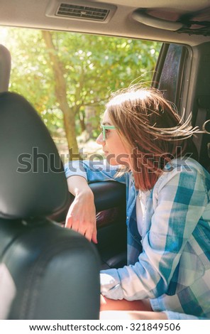 Portrait of beautiful young woman with sunglasses looking the landscape through the window car in a sunny day