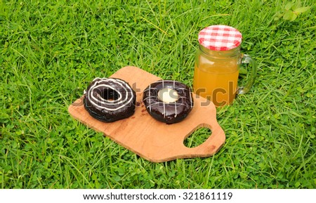 Freshly baked donuts on wooden tray on grass background.