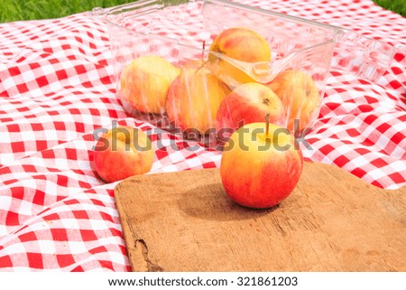 Fresh apples on a red and white checked cloth and hamper.