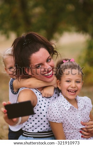 Mother and two daughters taking selfie in nature