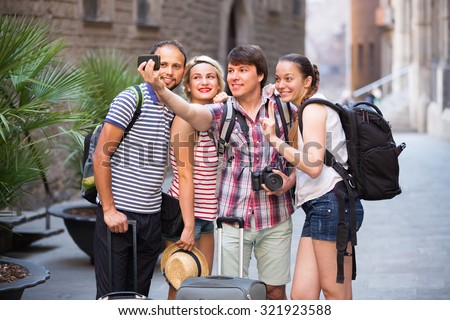 Young smiling travelers walking through the city and doing selfie
