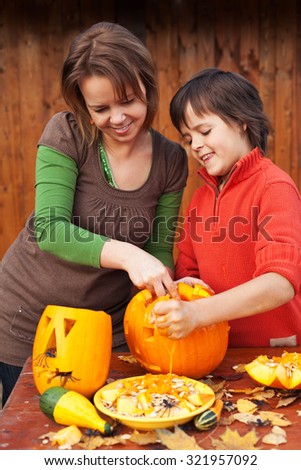 Young boy and woman carving a jack-o-lantern - preparing for halloween