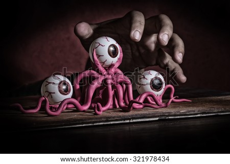 dark hand on top of octopus monster with dark red background