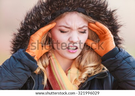 Portrait of pretty fashionable woman suffering from headache pain. Young girl in jacket with hood caught cold flu virus. Autumn fall winter fashion.
