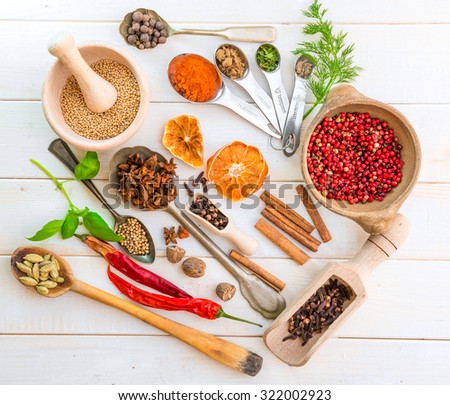 spoons with herbs and spices on white wooden background