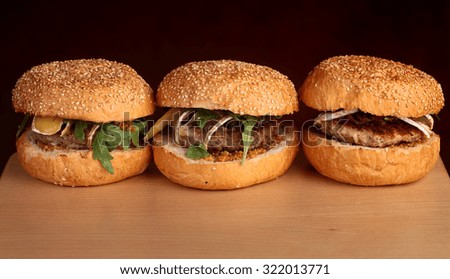 Big tasty appetizing fresh burgers of green lettuce red tomato cheese and bacon slice meat cutlet and white bread bun with sesame seeds closeup, horizontal picture