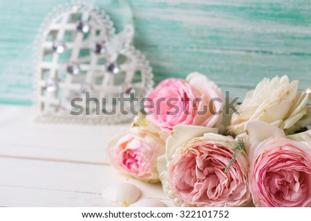 Sweet pink roses flowers and heart on white painted wooden background against turquoise wall. Selective focus. 